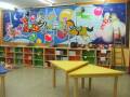 Escuela infantil con mesa de aprendizaje y murales temáticos.