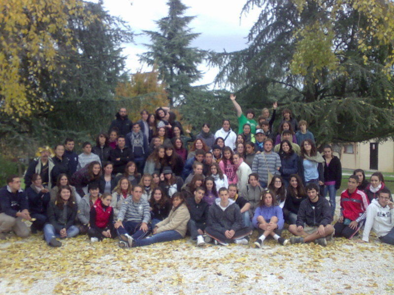 Un grupo de personas posando juntos en un parque con árboles y hojas caídas al suelo.