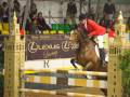 Jinete en competencia de salto de obstáculos con caballo, en un evento de lujo patrocinado por Lexus.