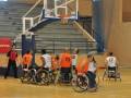 Jugadores de baloncesto en silla de ruedas en una cancha deportiva, participando en un partido.