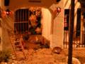 Miniatura de una casa rural con animales y flores, iluminada con luces rojas.
