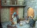 Escena navideña con figuras de pesebre en una casa medieval, incluyendo un burro y ovejas.