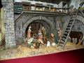 Escena navideña con figuras humanas y animales en un entorno de madera y piedra.