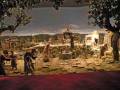 Escena pastoral con personas en vestimentas antiguas, animales y estructuras de piedra.