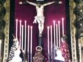 Imagen de una procesión religiosa con un crucificado en el centro, rodeado por velas encendidas y personas vestidas de trajes tradicionales.
