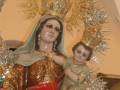Imagen de una Virgen María con un niño en sus brazos, rodeada por adornos dorados y cristales.