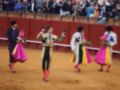 Tres toreros celebran en la plaza de toros, uno de ellos levanta el sombrero en saludo.