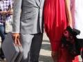 Imagen de un hombre en traje gris y una mujer con vestido rojo, posando juntos.