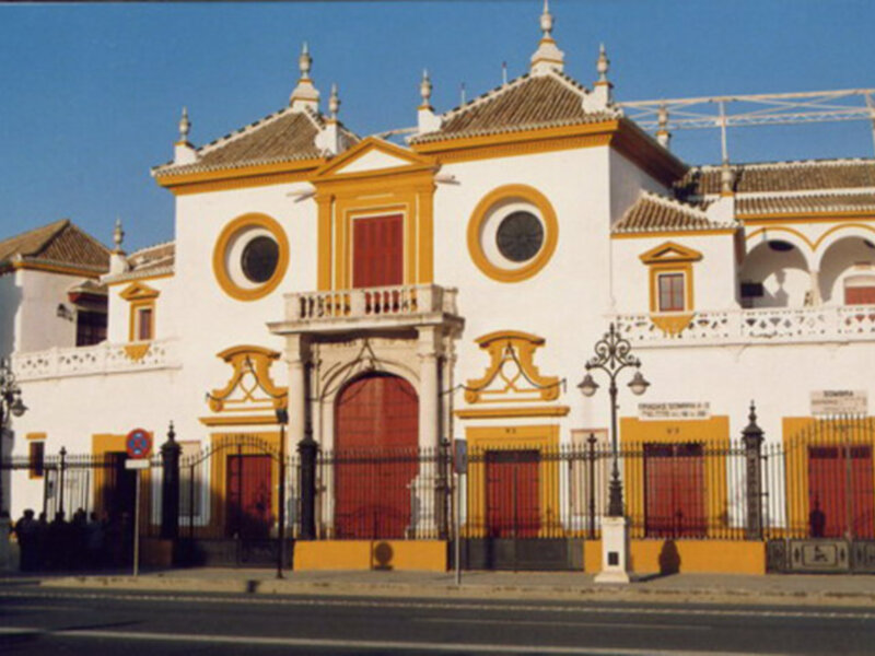 Fachada histórica de la plaza de toros de Sevilla, España, con su arquitectura distintiva y detalles decorativos.