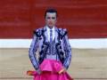 Un torero en traje de luces, con un pañuelo rosa y una camisa blanca.