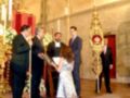 Una ceremonia religiosa en una iglesia con un altar, velas y decoraciones navideñas. Un grupo de personas, incluyendo una niña en un vestido largo y zapatos altos, se encuentran cerca del altar. La imagen muestra una atmósfera festiva y solemnemente ceremonial, con detalles que sugieren un evento importante o tradicional.
