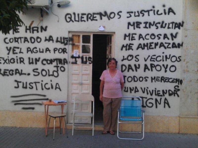 Una mujer se encuentra frente a una pared con grafitis que denuncian abusos y falta de justicia.