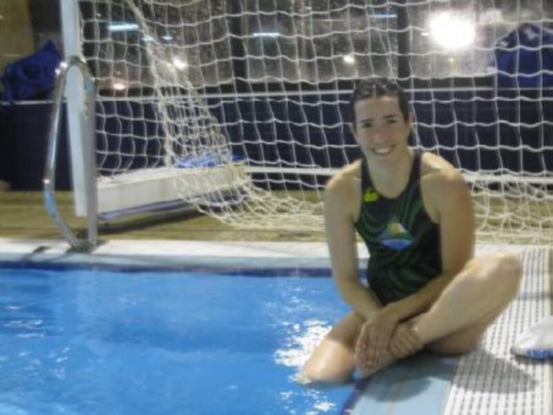 Una joven posando frente a una portería de fútbol en una piscina, iluminada por luces de techo.