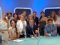 Una escena de un programa de televisión en el que una persona está sentada frente a otros participantes. La escena tiene un fondo azul y los participantes están sentados en una mesa con micrófonos.