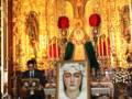 Una imagen religiosa en un altar dorado, con una figura central y velas rojas. En el frente hay una imagen de la Virgen María en un lienzo. La audiencia está presente, con algunas personas sentadas y otras de pie.