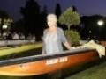 Un hombre camina con una canoa en un parque iluminado por la noche, rodeado de árboles y luces.