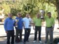 Equipo ganador de un torneo de boliche, posando con sus trofeos en un entorno verde y tranquilo.