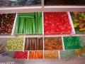 Una colección de dulces de colores brillantes en diferentes formas y texturas, incluyendo caramelos, caramelitos y otros tipos de caramelos, organizados en una exhibición de cristal.