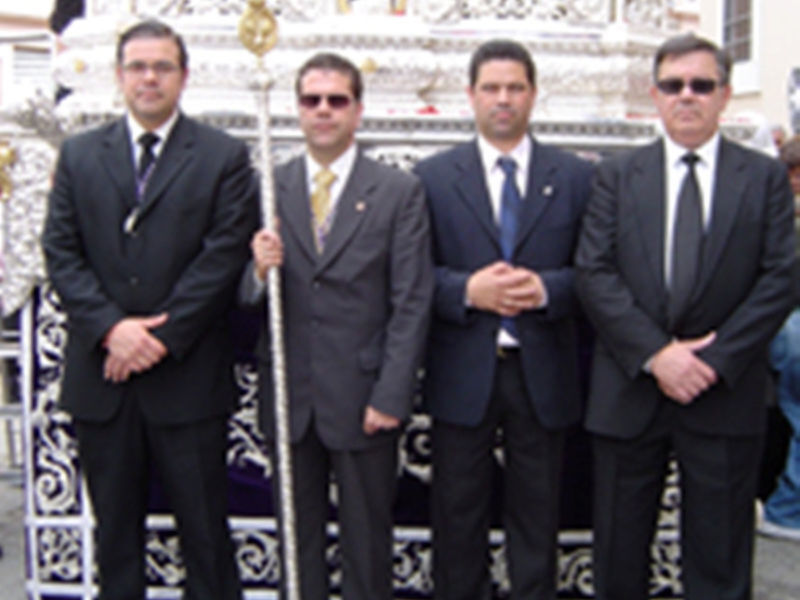 Cuatro hombres en trajes formales posan frente a un monumento histórico.