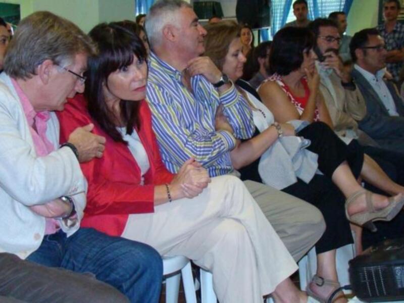 Una audiencia de personas sentadas en sillas, concentradas en algo que no se puede ver en la imagen.