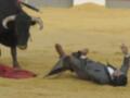 Un torero caído en el suelo de arena, rodeado por una muleta y un traje tradicional.