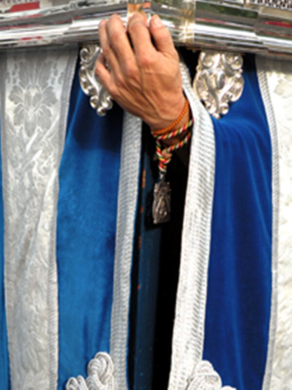 Man wearing a blue robe with silver and white details, holding a silver object.