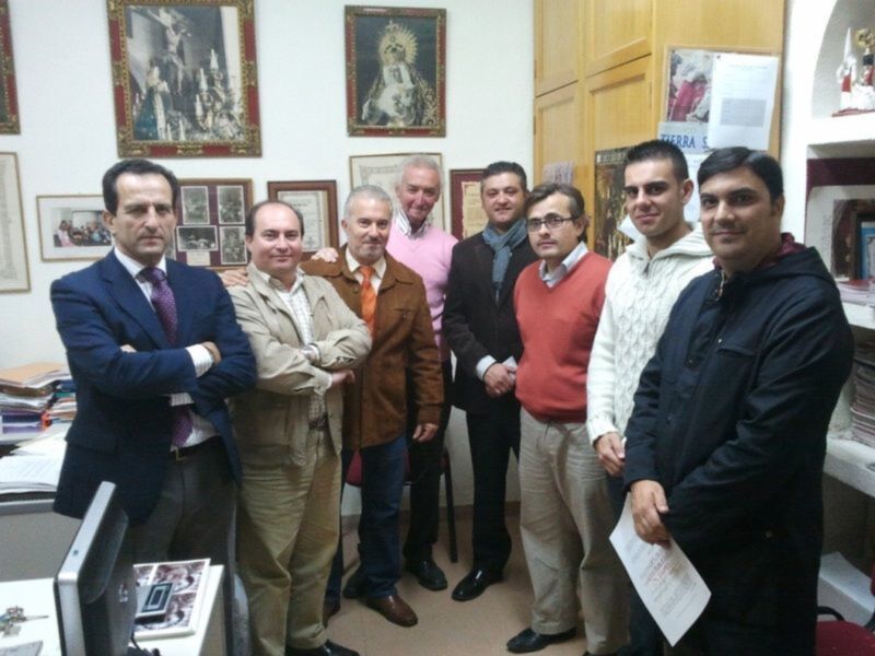 Un grupo de personas posando en un despacho, con carteles y fotos en las paredes.