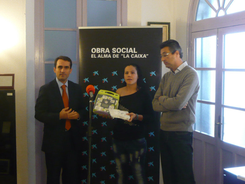 Un evento de presentación de una obra social, con una mujer en el centro, dos hombres a su izquierda y un cartel de la obra social en el fondo.