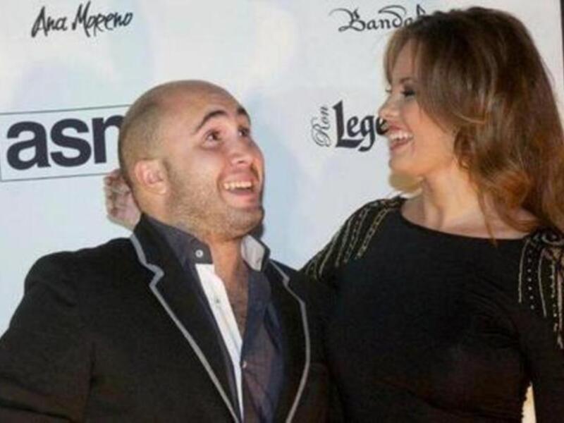Dos personas sonrientes posando juntas en una alfombra roja.