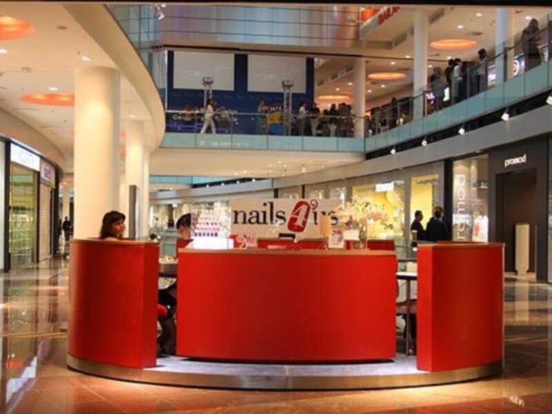 Un mostrador de ventas en un centro comercial con una pantalla de televisión en el fondo y personas en el centro.