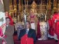 Una imagen de una ceremonia religiosa en un templo, con personas vestidas con vestidos rojos y un altar en el fondo.
