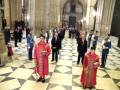 Imaginación de un evento formal en un palacio, con personas vestidas formalmente y decoraciones elegantes.