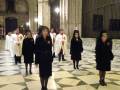 Personajes en trajes litúrgicos caminando en el interior de una catedral con suelo de mosaico.