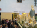 Imaginación de una procesión religiosa en una residencia llamada Residencia San Eugenio, con una imagen de la Virgen María en el centro, rodeada de flores y velas.