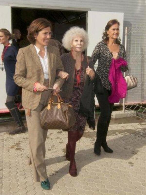 Tres mujeres caminando juntas, una con cabello largo y rizado, otra con cabello blanco y otra con cabello largo y oscuro, vestidas con ropa casual y elegante, en un entorno urbano.