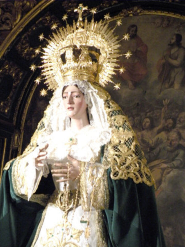 Imagen de una Virgen con vestimenta tradicional, coronada y rodeada por estrellas. Contexto religioso o devocional.