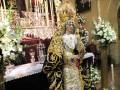 Procesión de la Virgen del Rocío en una iglesia, con vestimenta tradicional y ofrendas florales.