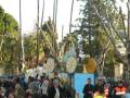Desfile de carros de fiesta en un parque público, con personas disfrutando de la celebración.