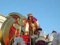 Imaginación creativa en un desfile navideño, con personajes en trajes elaborados y un fondo de cielo azul claro.