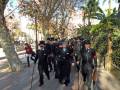Imaginación de un grupo de personas en uniforme militar caminando por una calle con árboles y palmeras.