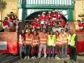 Voluntarios y participantes en una celebración festiva en una plaza histórica.