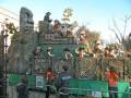 Desfile temático con carroza decorada como un antiguo templo maya, personajes vestidos de exploradores y seguidos por seguridad.
