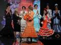 Una escena de desfile de moda con modelos vestidos en trajes tradicionales flamencos.