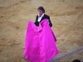 Un torero sostiene una capa roja en una plaza de toros.