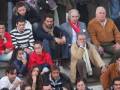 Una multitud de personas sentadas en un estadio, algunos con bufandas y chaquetas. La imagen muestra a diversos espectadores de diferentes edades, posiblemente en un partido deportivo.