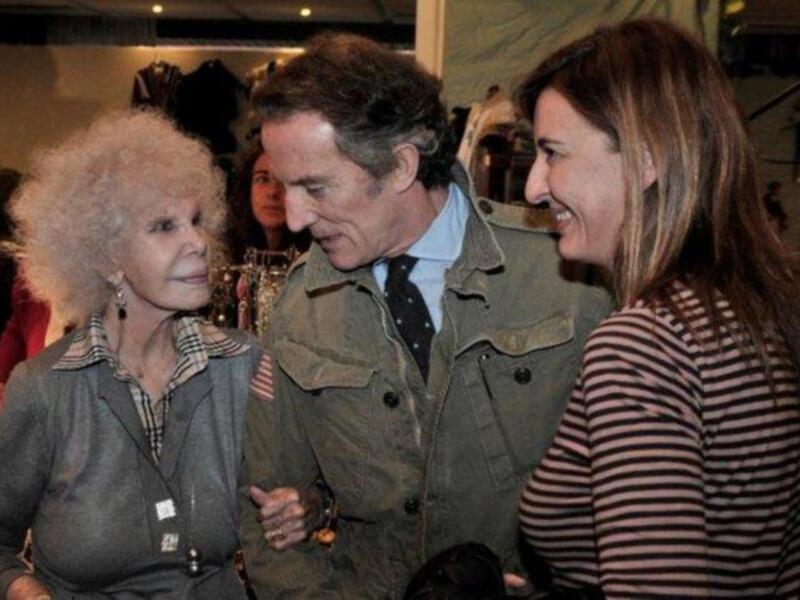 Una imagen de dos personas en un evento, con una mujer en el centro y una mujer a su lado, ambos sonrientes y con expresiones felices.