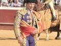 Un rejoneador en el centro de la plaza de toros, con su muleta y capote, preparándose para el toro.