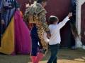 Un torero y un niño caminan juntos en el ruedo de una corrida de toros.