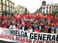 Manifestación con pancarta '29M Huelga General' y banderas rojas, reclamando una huelga general contra el control total.