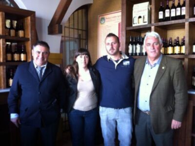 Cuatro personas posan frente a una pared de botellas de vino en un ambiente elegante.